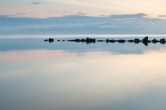 Breakwater Rocks in Calm Sea with clouds and reflextions in the water.