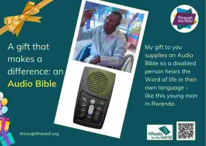 An e-card on a dark green background, with text on the left that says: 'A gift that makes a difference: an Audio Bible’ To the right are 2 photos: a close-up photo of a solar-powered audio Bible (which looks like a small mobile phone); a smiling young Rwandan man holding an Audio Bible up in the air, as he sits in a wheelchair. Below the images is text saying: 'My gift to you supplies an Audio Bible so a disabled person hears the Word of life in their own language - like this young man in Rwanda. There are logos for Through the Roof www.throughtheroof.org and their project Wheels for the World. There is also a QR code linking to their International Missions page at https://runyourownwebsite.uk/ttr/international-mission/