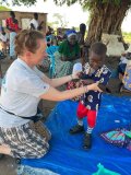 A wheels team member helps Peter, a young boy, to stand up in his new pediactric boots