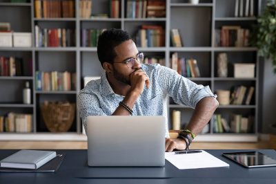 A person at a laptop, thinking what to write about