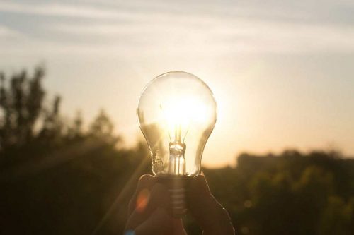 A lightbulb held up outside with sunlight coming through it