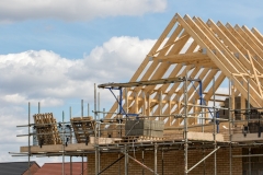 Timber framework of house roof trusses with scaffold on a building being built on a new housing estate.