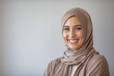Portrait of a young woman in traditional Muslim clothing, smiling.